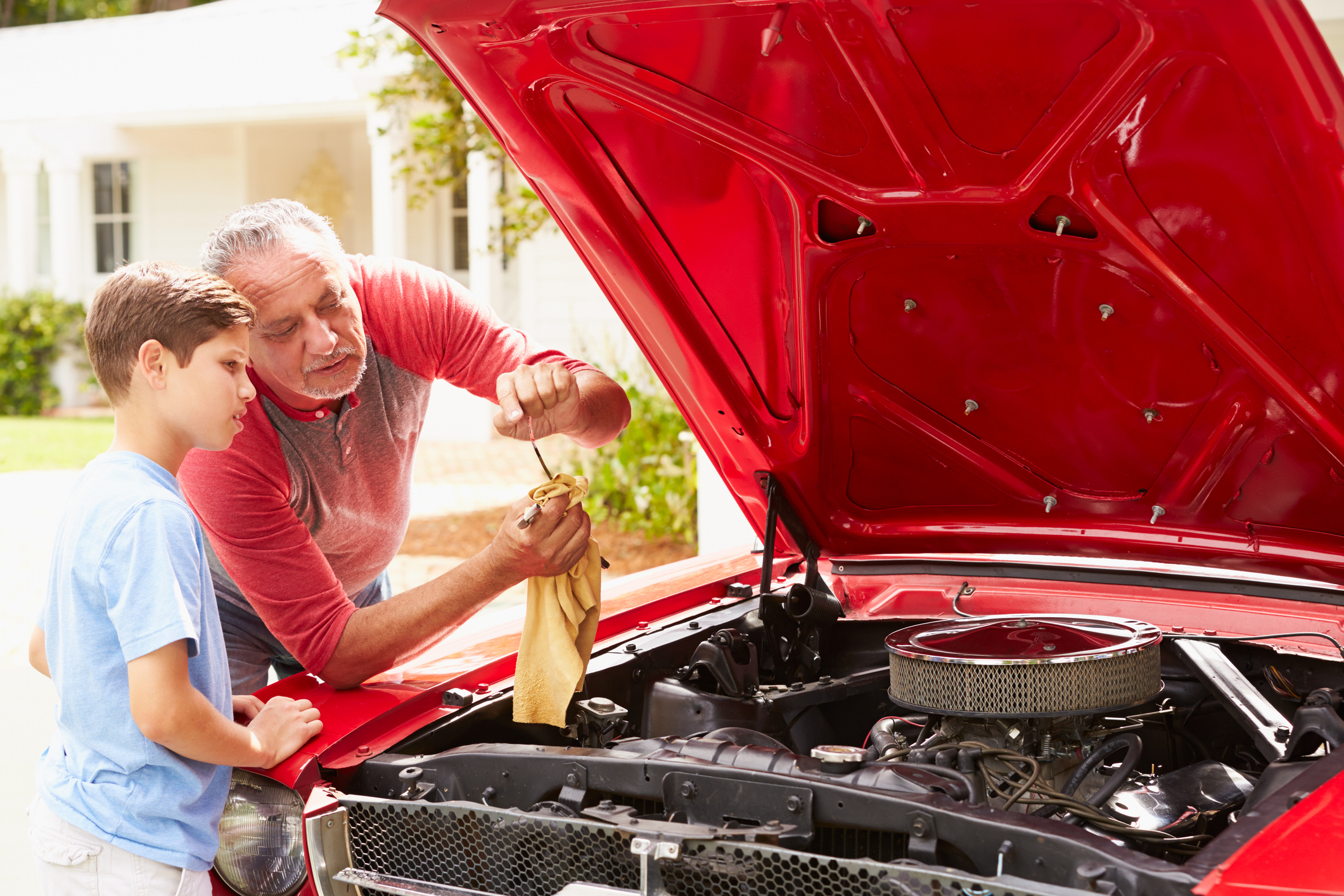 A boy and an older man working on the engine of a car.