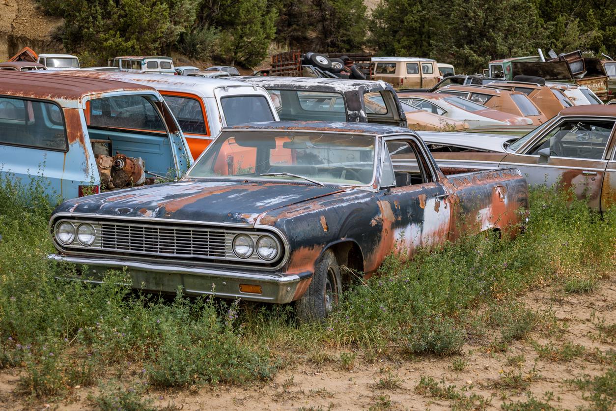 Rusted, vintage cars on a salvage lot.
