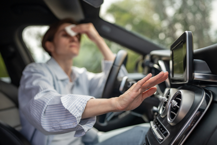 A driver overheating in a car trying to cool off with AC.