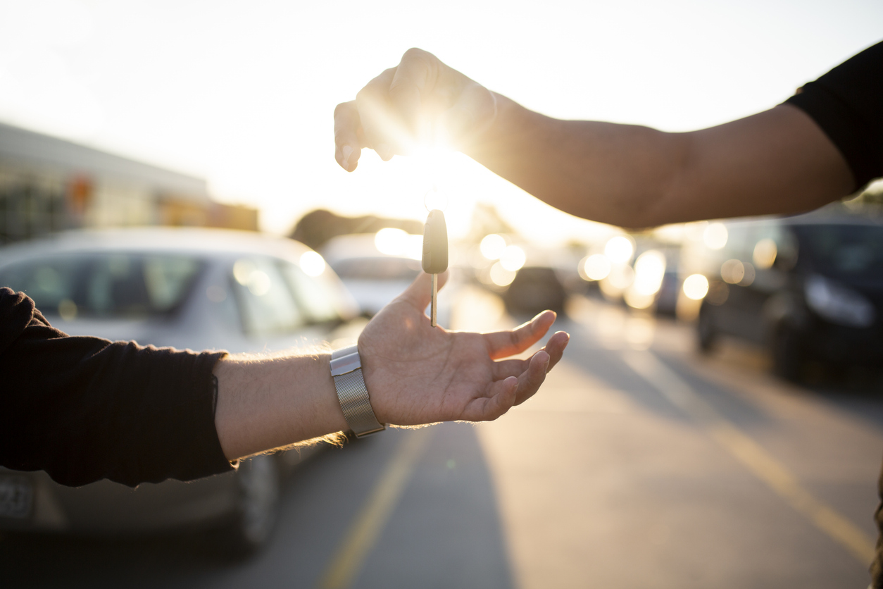 Keys to a car being passed from an owner to a dealer. 